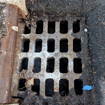 Clean inlet grate on the curbside of a city street.