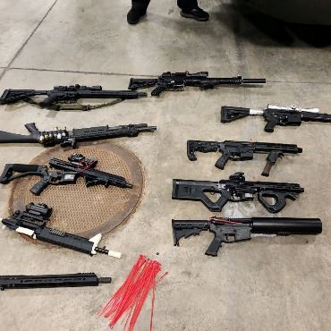 About 10 different recovered guns laid out on the floor by police.