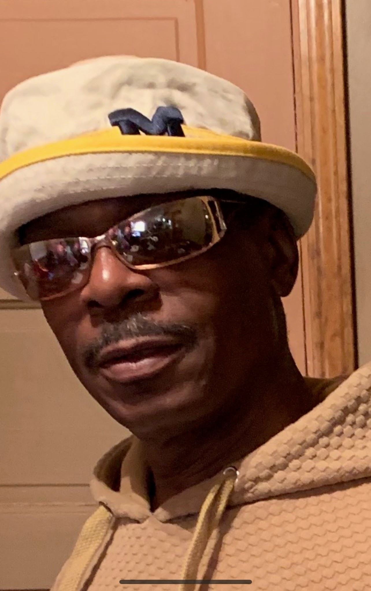 Black man with mustache, wearing U of M bucket hat, sunglasses and hoodie.